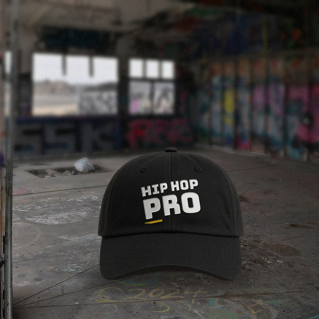 Svart HIP HOP PRO-kaps på betonggulv foran graffitivegger